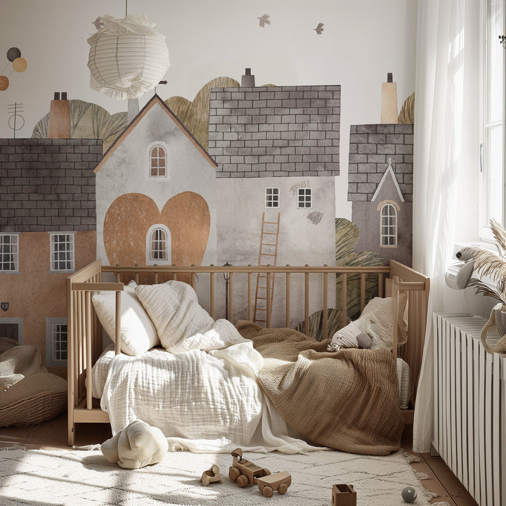 Nursery room with wooden crib, toys, and wall mural of houses.